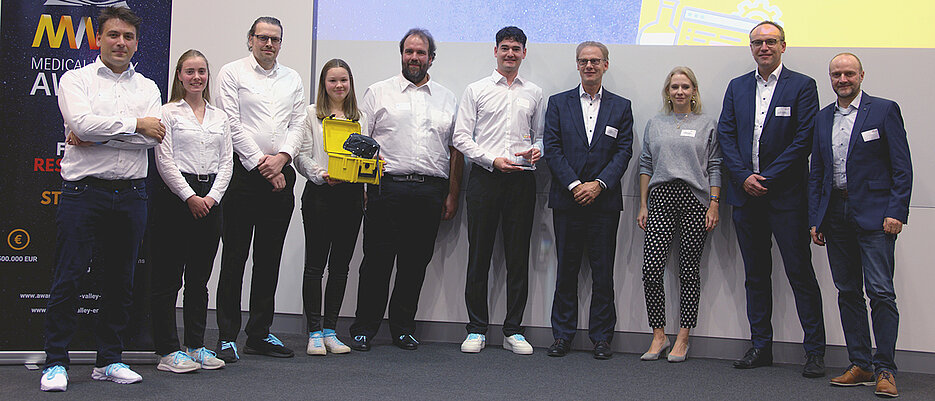 Übergabe des Medical Valley Awards. Von links nach rechts: Das StrokeCap-Team bestehend aus Dr. Patrick Vogel, Johanna Günther, Dr. Martin Rückert, Teresa Reichl, Prof. Dr. Volker Behr, PD Dr. med. Stefan Herz, der Vertreter des Staatsministeriums Dr. Thomas Krammer sowie die Mitglieder der Jury und des Medical Valley EMN e.V Marina Moskvina, Marco Wendel, Dr. Jörg Stein. 